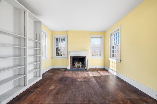 unfurnished living room featuring a brick fireplace and dark hardwood / wood-style flooring