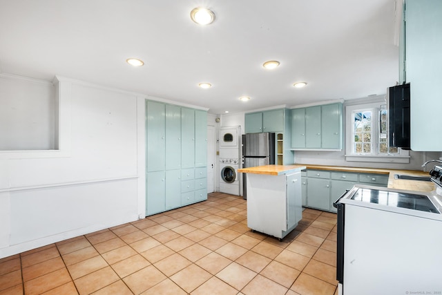 kitchen with a kitchen island, butcher block countertops, stacked washing maching and dryer, range with electric cooktop, and stainless steel fridge