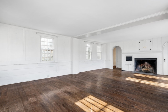 unfurnished living room featuring dark wood-type flooring and ornamental molding