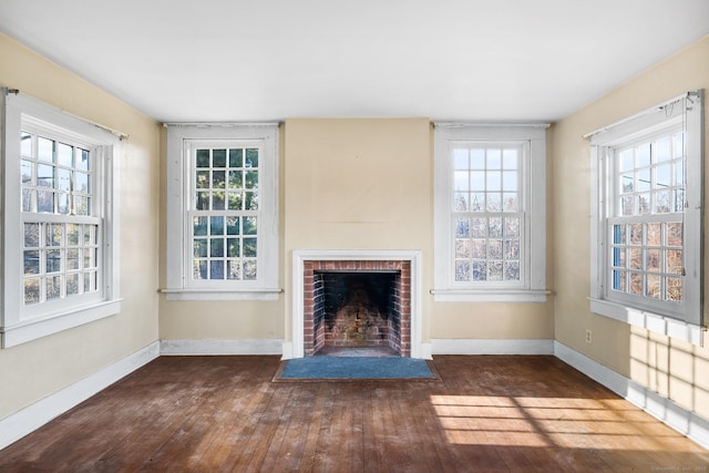 unfurnished living room with dark wood-type flooring and a brick fireplace