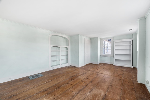 empty room featuring built in features, dark hardwood / wood-style flooring, and crown molding