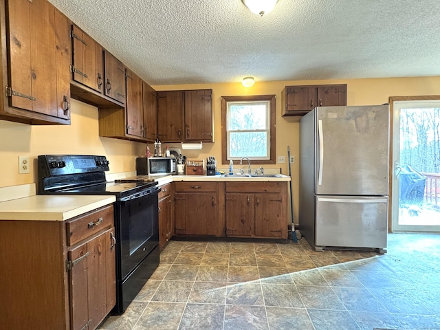 kitchen with sink, a textured ceiling, and appliances with stainless steel finishes