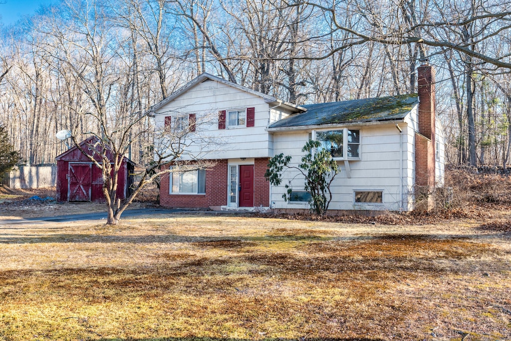 split level home with a front yard and a storage shed