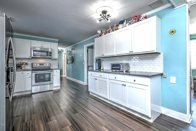 kitchen featuring crown molding, white cabinetry, stainless steel appliances, tasteful backsplash, and dark stone counters