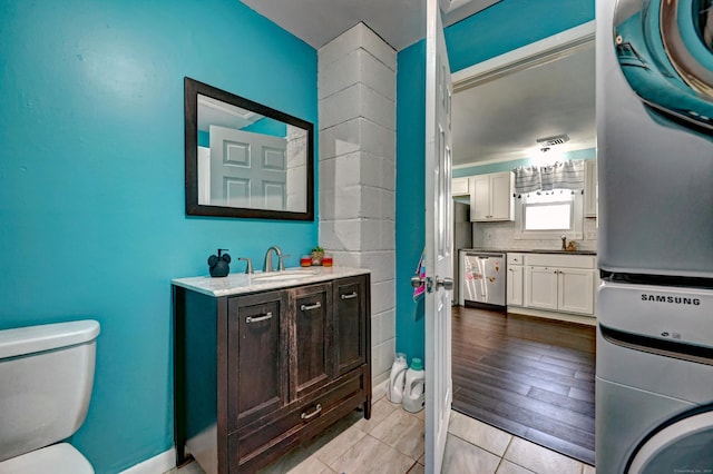 bathroom featuring hardwood / wood-style floors, decorative backsplash, vanity, stacked washer and clothes dryer, and toilet