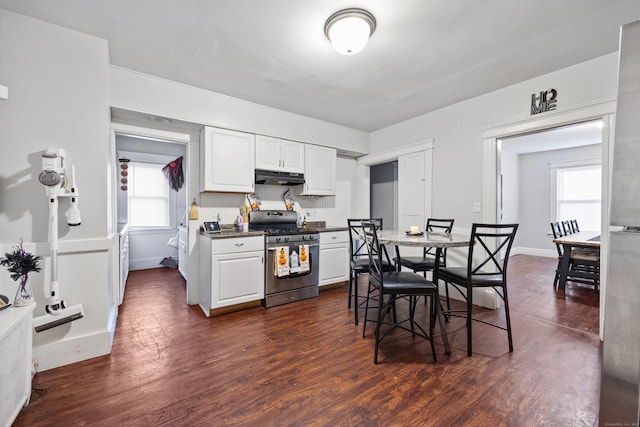 kitchen featuring white cabinets, dark countertops, dark wood-type flooring, stainless steel gas range, and under cabinet range hood