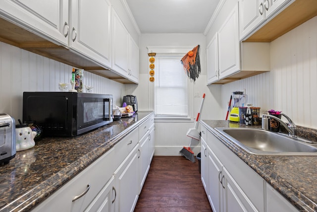 kitchen with black microwave, dark wood finished floors, a sink, and white cabinetry