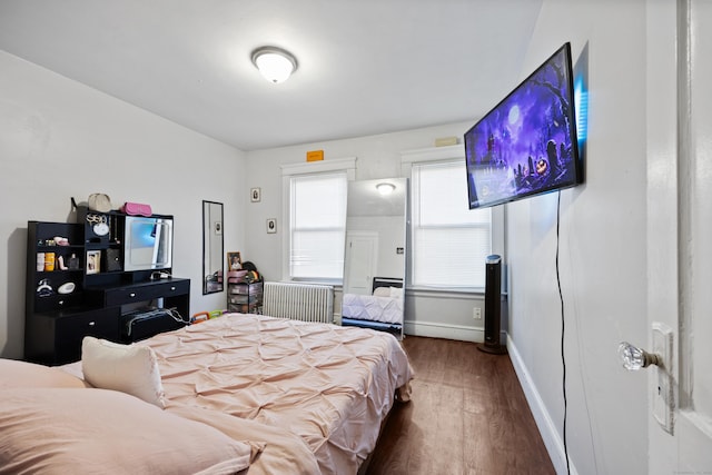 bedroom featuring dark wood-style floors, radiator heating unit, and baseboards