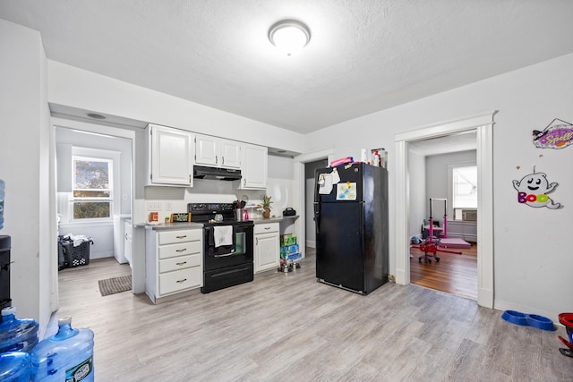 kitchen with white cabinetry, a textured ceiling, light wood-type flooring, under cabinet range hood, and black appliances