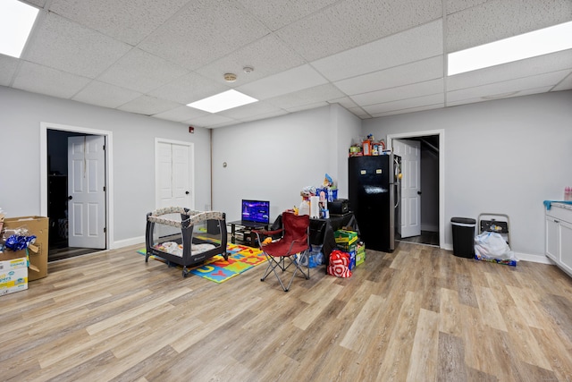 game room featuring light wood-style flooring, baseboards, and a drop ceiling