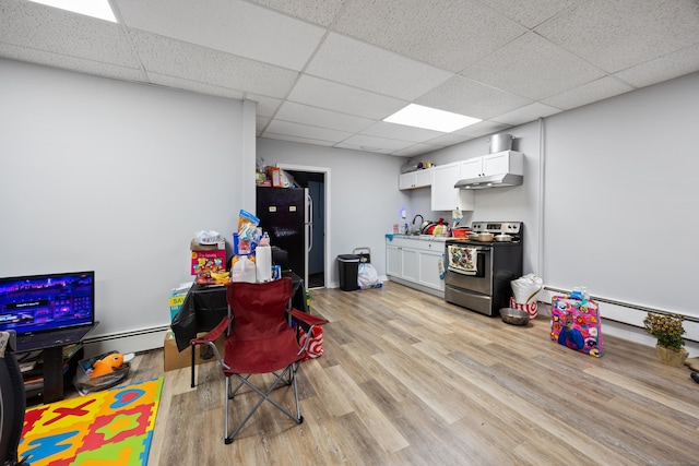 recreation room featuring a drop ceiling, a baseboard radiator, and light wood-style floors