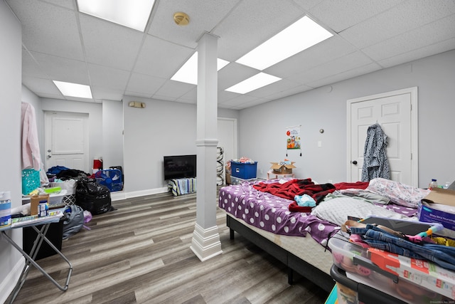 bedroom with a drop ceiling, wood finished floors, and baseboards