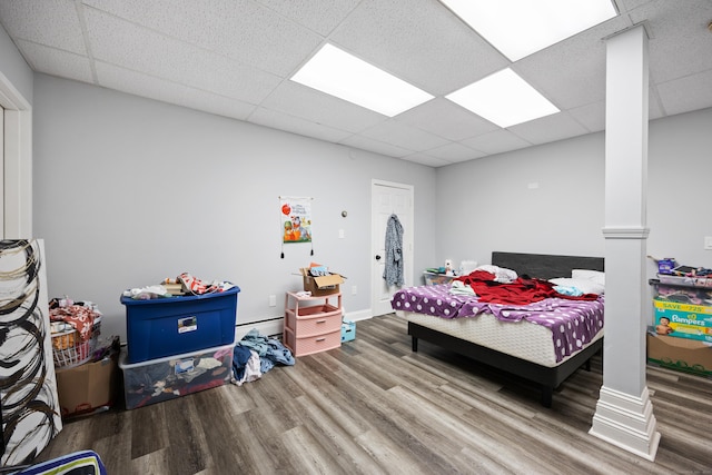 bedroom featuring a drop ceiling, baseboards, and wood finished floors