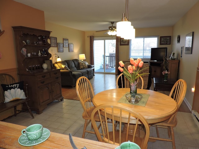 tiled dining space with ceiling fan and a baseboard radiator