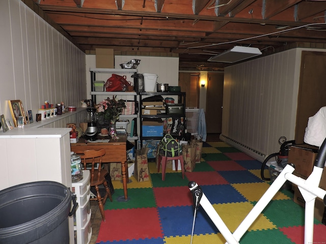 basement with a baseboard heating unit and wood walls