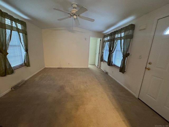 empty room featuring ceiling fan, a wealth of natural light, vaulted ceiling, and carpet