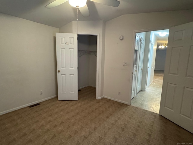 unfurnished bedroom featuring a closet, carpet floors, a spacious closet, lofted ceiling, and ceiling fan with notable chandelier