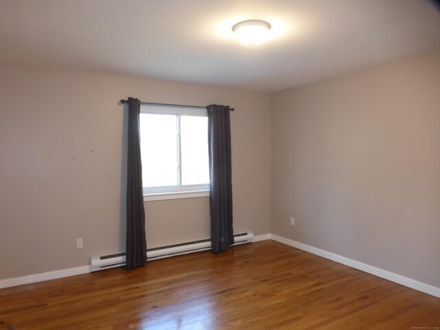 unfurnished room featuring hardwood / wood-style flooring and baseboard heating