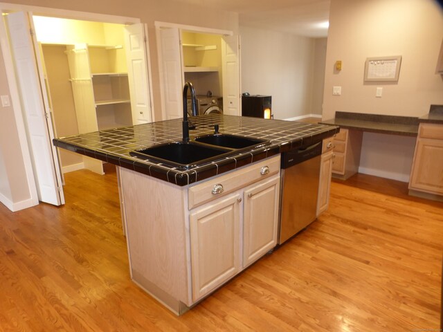 kitchen with dishwasher, tile counters, light brown cabinets, sink, and a kitchen island with sink