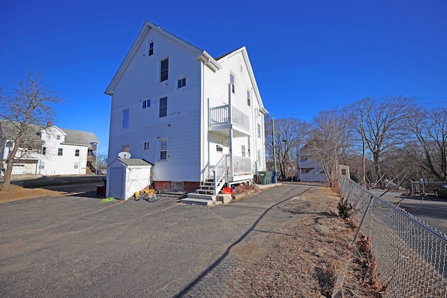 view of home's exterior featuring a balcony, cooling unit, and a storage shed