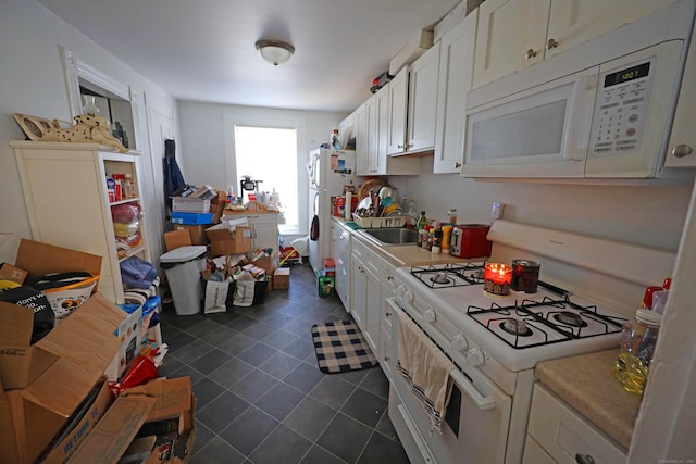 kitchen with white appliances, white cabinets, and sink