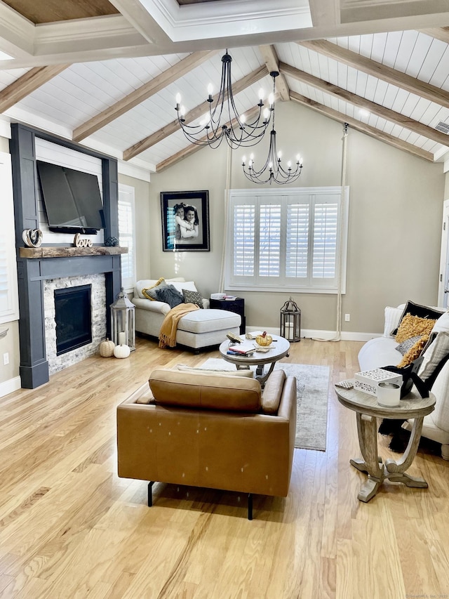 living room with light hardwood / wood-style flooring, a stone fireplace, lofted ceiling with beams, and a wealth of natural light