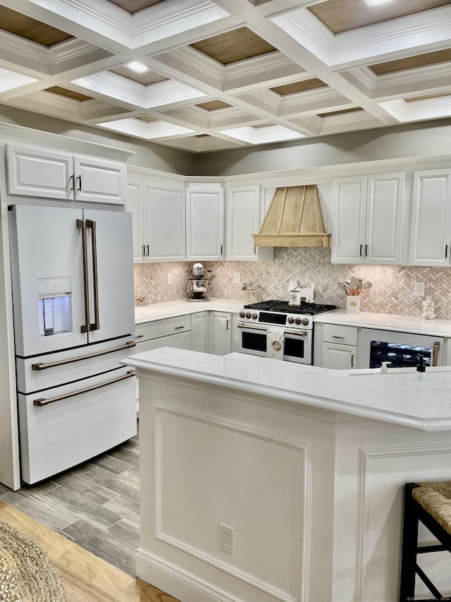 kitchen featuring premium range hood, high quality appliances, light hardwood / wood-style floors, a breakfast bar area, and white cabinets