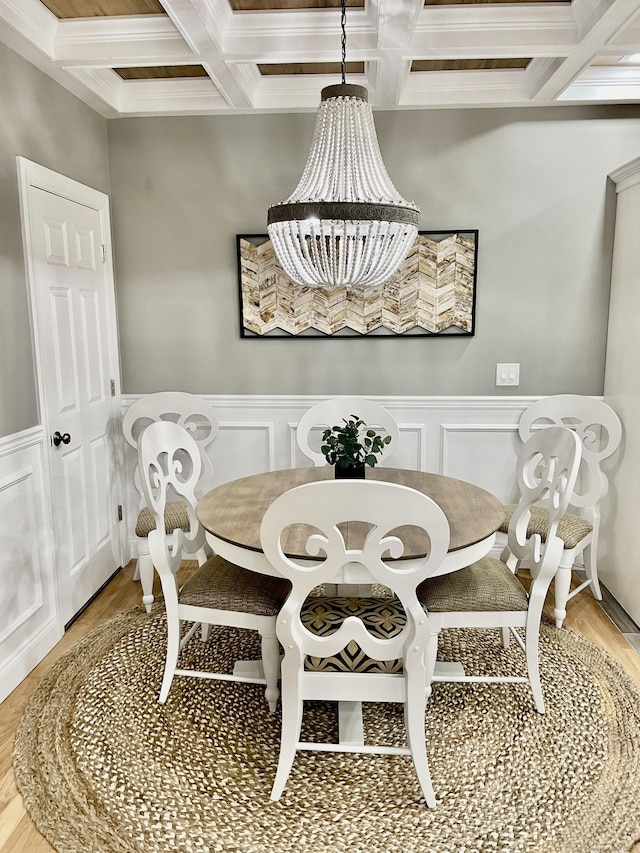 dining space with hardwood / wood-style floors, an inviting chandelier, beam ceiling, ornamental molding, and coffered ceiling