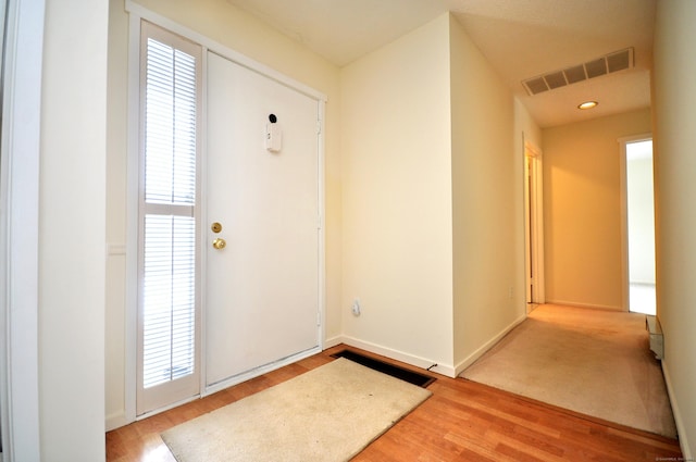 foyer entrance with wood finished floors, visible vents, a wealth of natural light, and baseboards