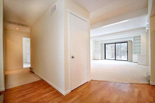 hallway with built in shelves, a baseboard radiator, and hardwood / wood-style floors