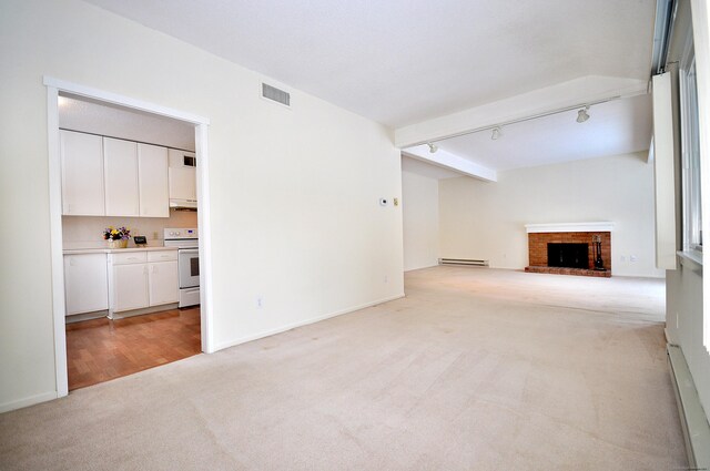 unfurnished living room featuring rail lighting, a brick fireplace, a baseboard heating unit, and light carpet