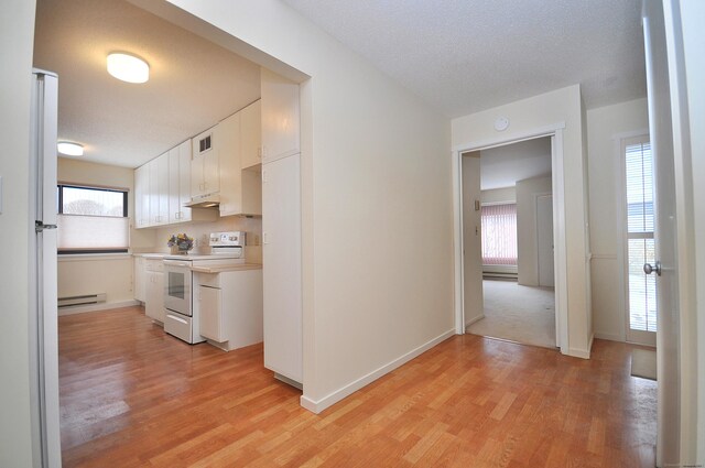 interior space with white cabinetry, white appliances, light hardwood / wood-style flooring, and a baseboard heating unit