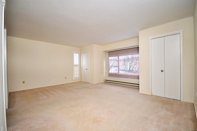 unfurnished bedroom featuring a baseboard radiator and light colored carpet