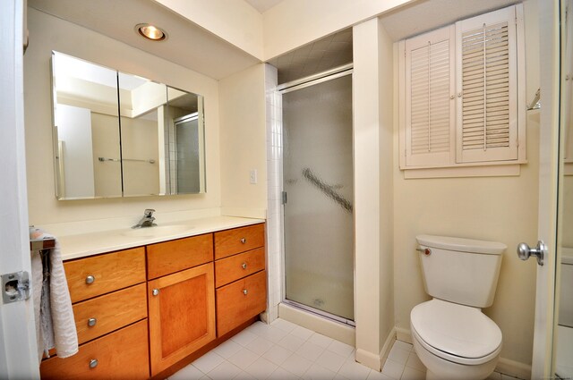 bathroom with walk in shower, vanity, toilet, and tile patterned flooring