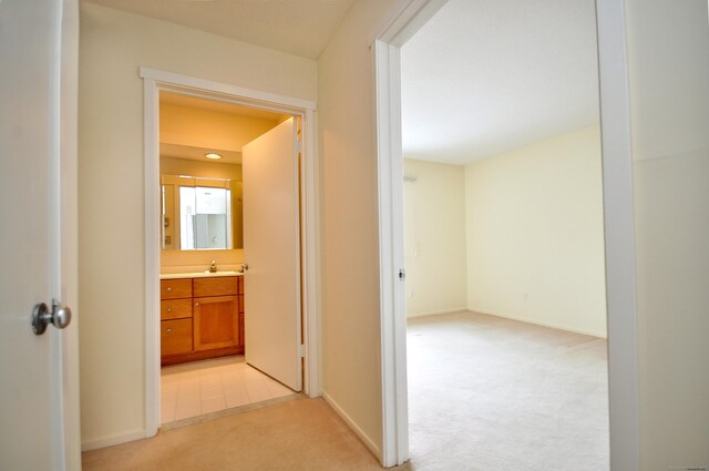 corridor featuring sink and light carpet