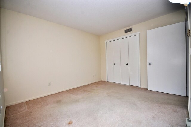 unfurnished bedroom with light colored carpet and a closet