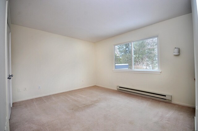 carpeted empty room featuring a baseboard radiator