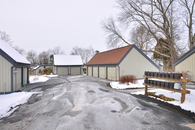 snow covered property with an outbuilding and a garage