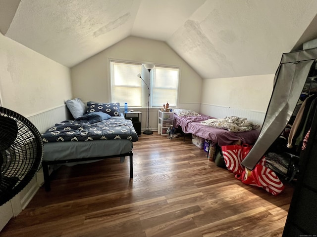 bedroom with lofted ceiling, dark wood-type flooring, and a textured ceiling