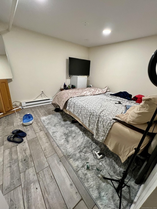 bedroom featuring hardwood / wood-style flooring and a baseboard heating unit