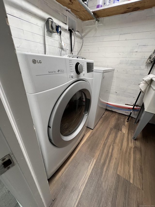 laundry area with dark wood-type flooring, independent washer and dryer, and wood walls