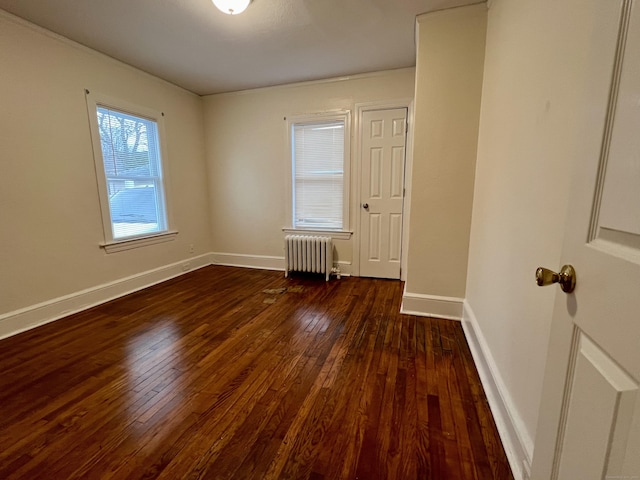 spare room with radiator heating unit and dark hardwood / wood-style floors