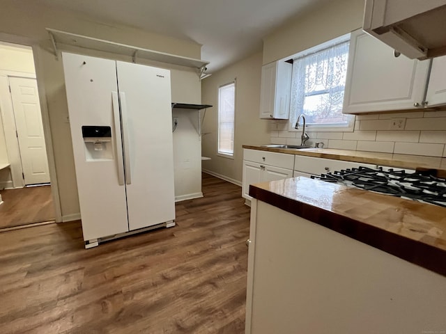 kitchen featuring sink, white refrigerator with ice dispenser, white cabinets, decorative backsplash, and light wood-type flooring