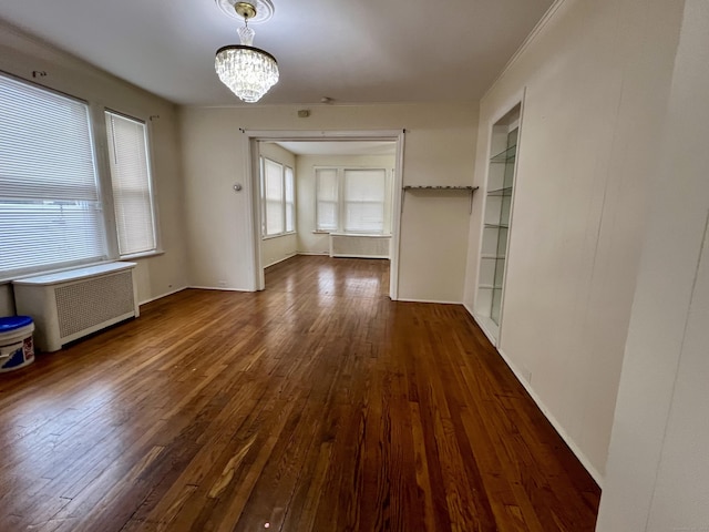 interior space with an inviting chandelier, radiator, built in shelves, and dark wood-type flooring