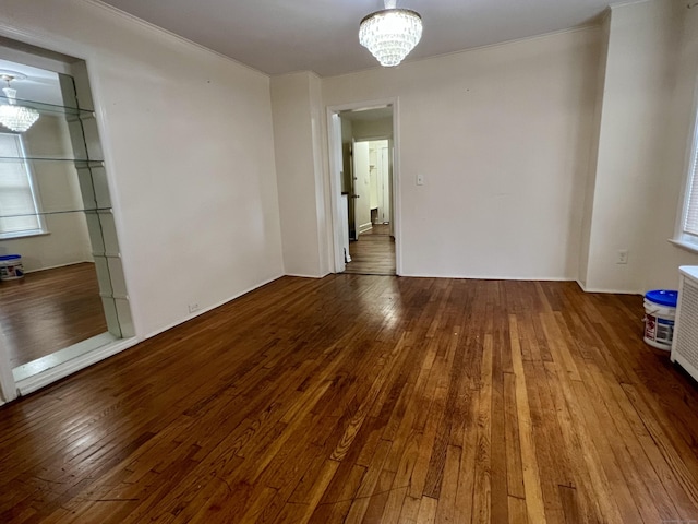 empty room featuring wood-type flooring and an inviting chandelier