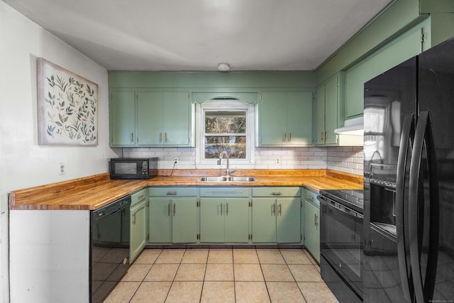 kitchen featuring green cabinets, light tile patterned floors, black appliances, wooden counters, and sink