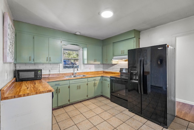 kitchen with sink, green cabinets, light tile patterned flooring, wood counters, and black appliances