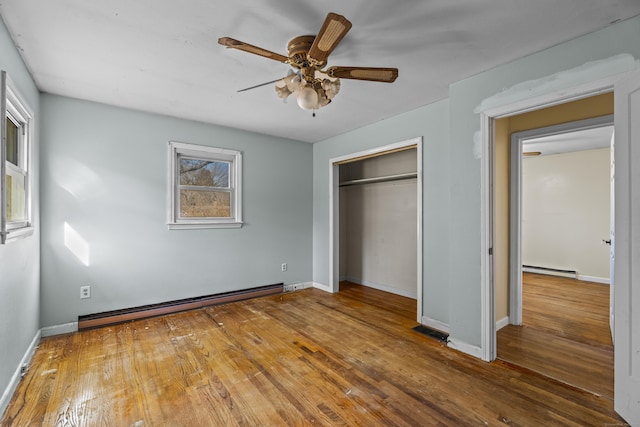 unfurnished bedroom with a closet, hardwood / wood-style floors, a baseboard heating unit, and ceiling fan