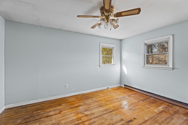 empty room featuring baseboard heating, ceiling fan, and hardwood / wood-style floors