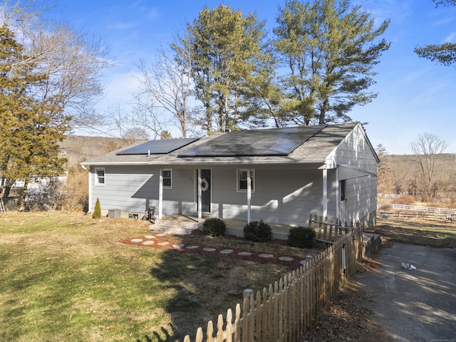 view of front of property with solar panels, covered porch, and a front lawn